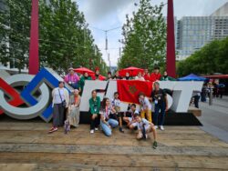 A group of young people posing in front of a FIRST Robotics sign.