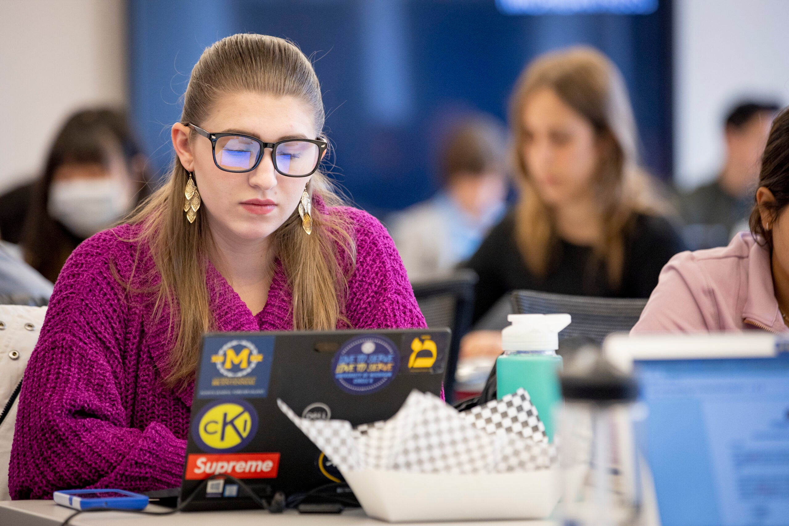 A girl sitting at a desk looking at her laptop.