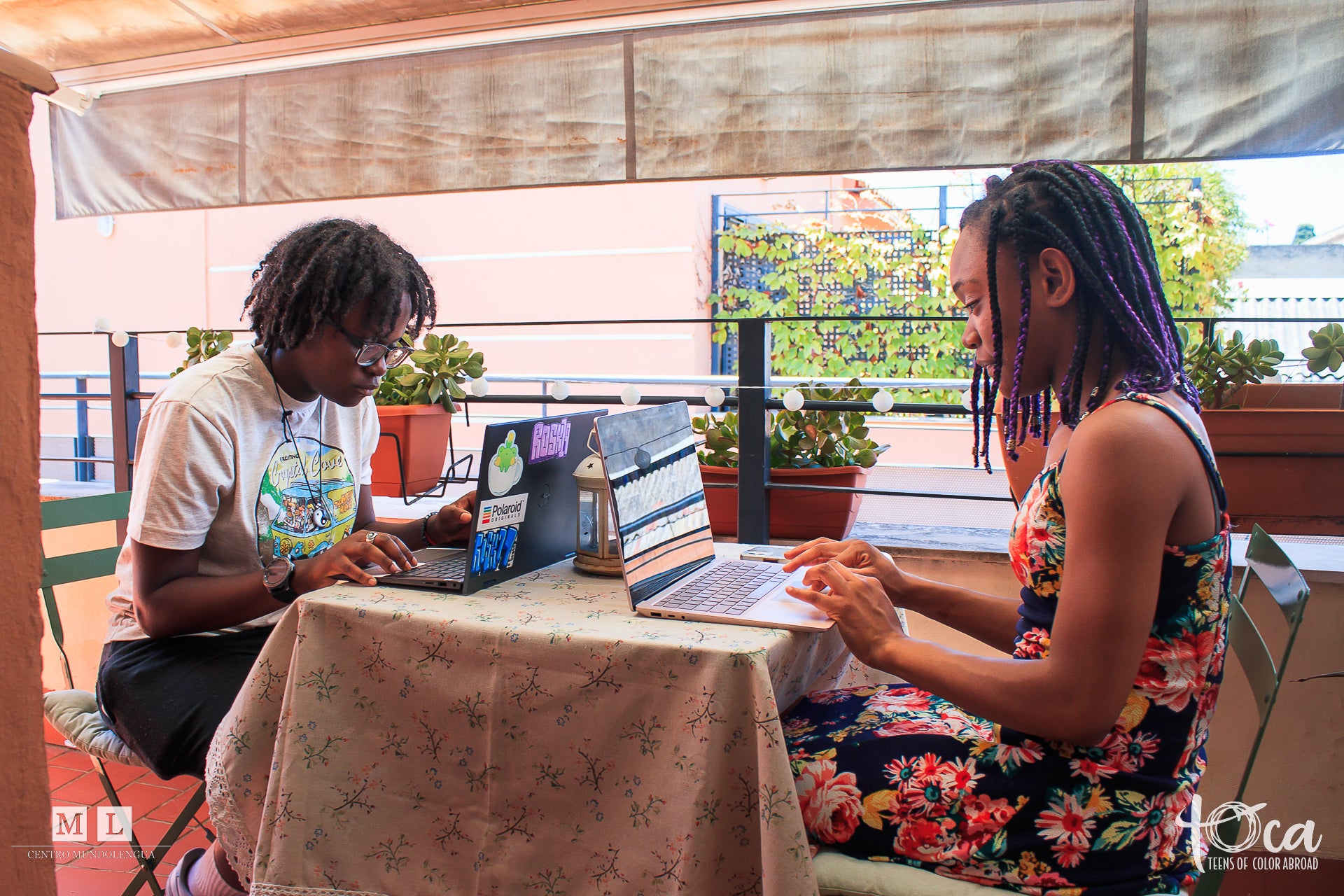 Two young people sitting across from each other at a table working on laptops.